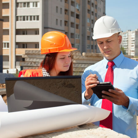 Two architects wearing protective helmet standing in front of building site